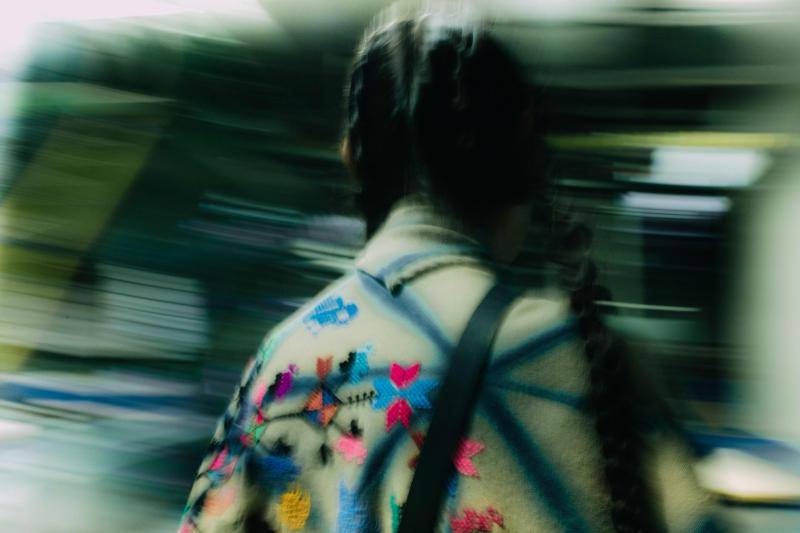 The back of a model wearng a poncho decorated in brightly colored shapes