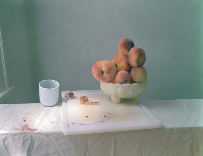 Photograph of a coffee cup and a bowl of peaches on a cutting board