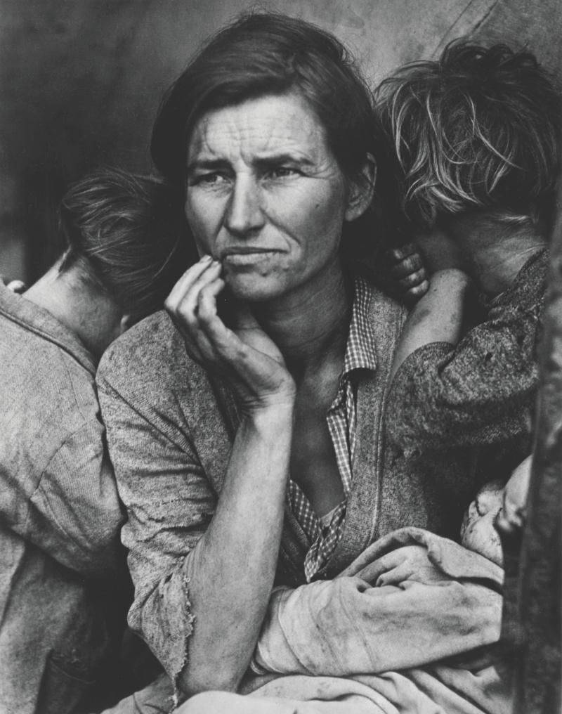 Black and white photograph of a worried migrant mother surrounded by her two children