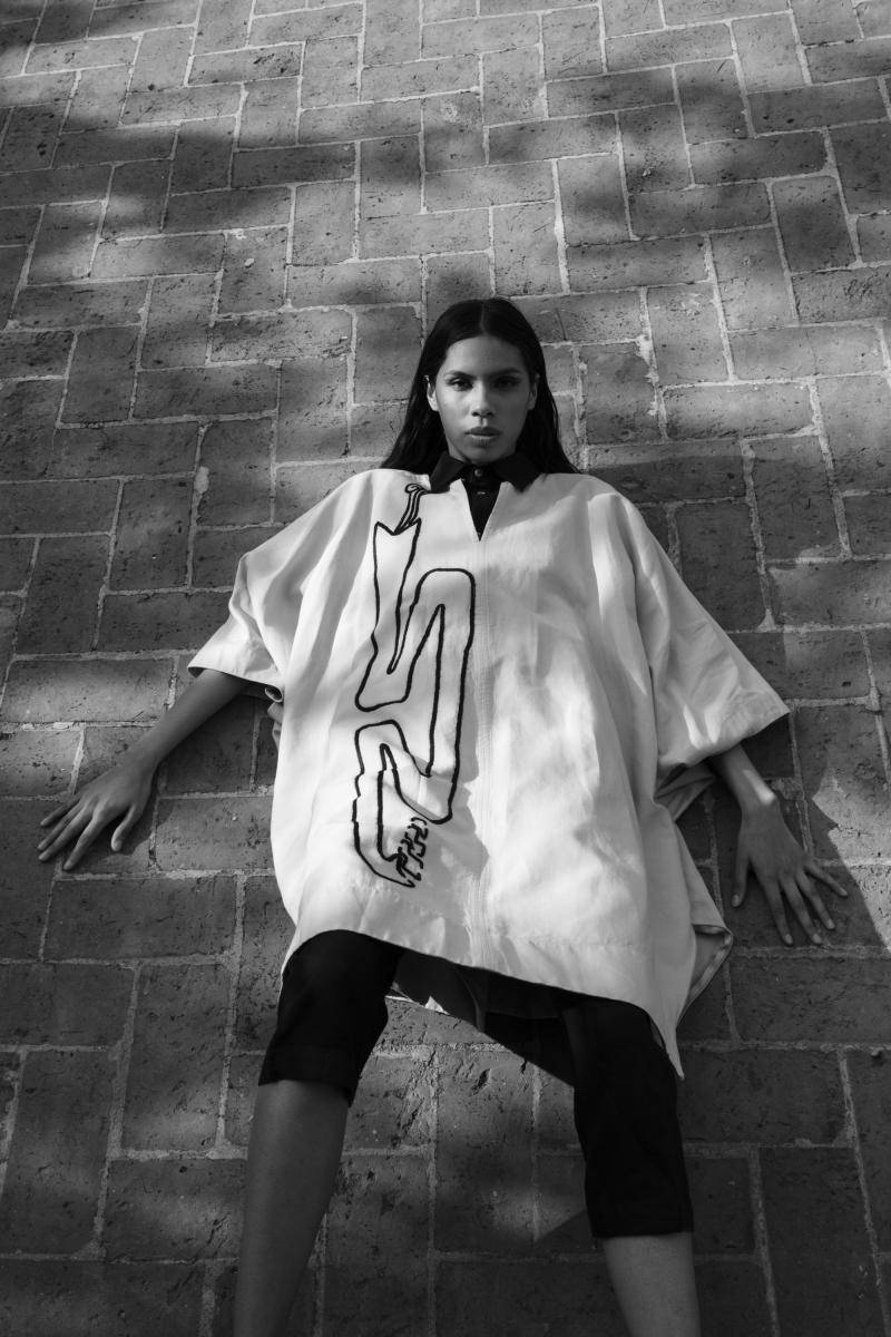 Black and white photo of a model wearing a white tunic