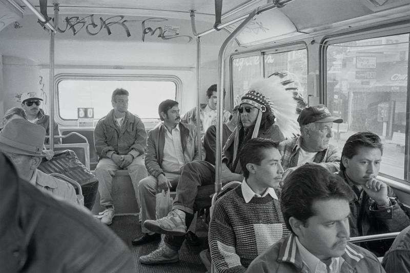 Black and white photograph from the 1950s of a Native American man sitting in a crowded bus
