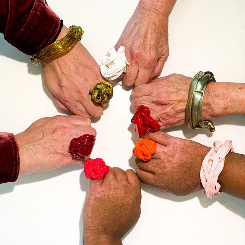 6 hands in a circle showing bracelets and rings designed by Gaetano Pesce
