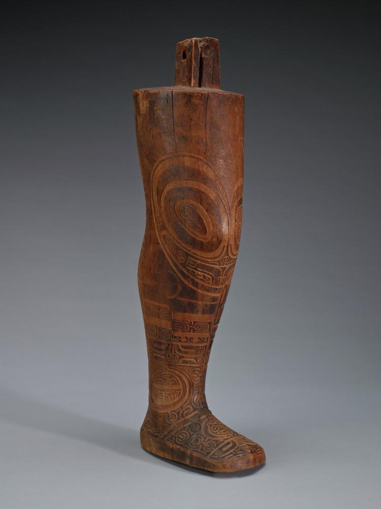 Bust of a leg made out of wood with symbolic patterns meant to resemble tattoos