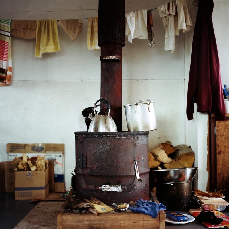 Interior view of a rural home with a stove, kettle, clothesline, and more in the frame