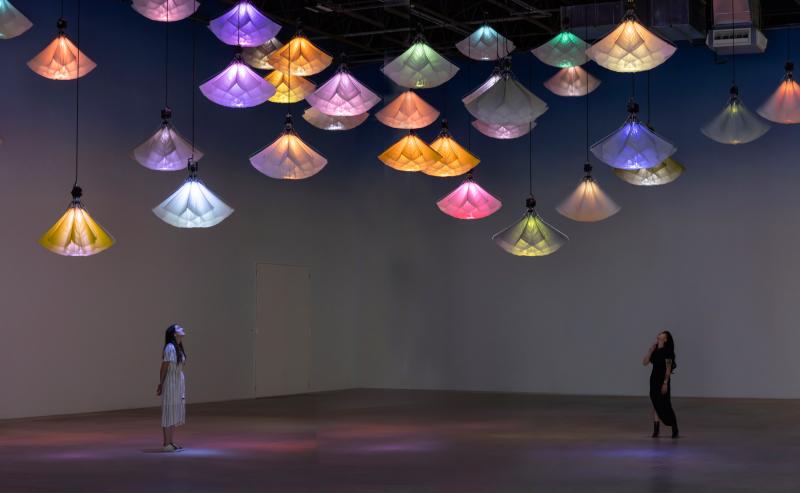Two visitors looking up at a group of hanging light installations