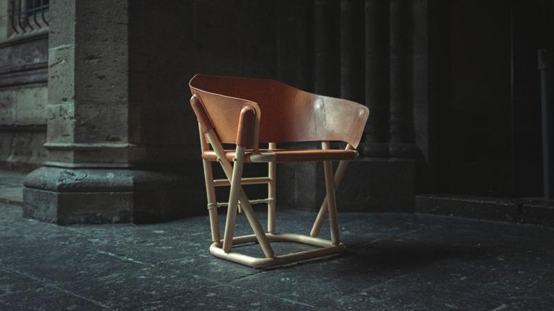 Small stool-like chair made out of beech wood and orange-colored leather