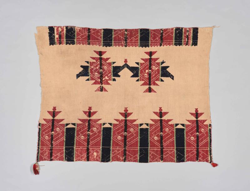 an Acoma Pueblo textile with red and black and green graphic designs embroidered on in