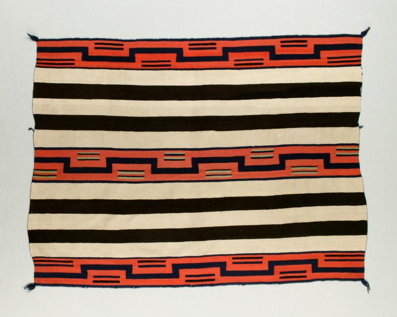 Red, black, and cream colored striped blanket designed by a Navajo artist