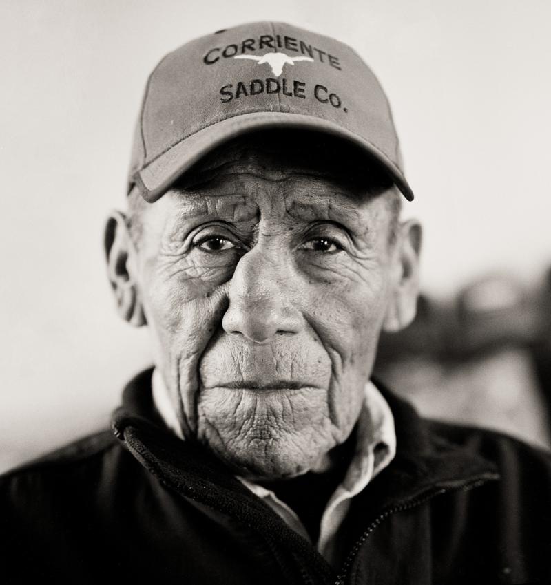 Black and white photograph of an older Native American gentleman wearin a baseball cap