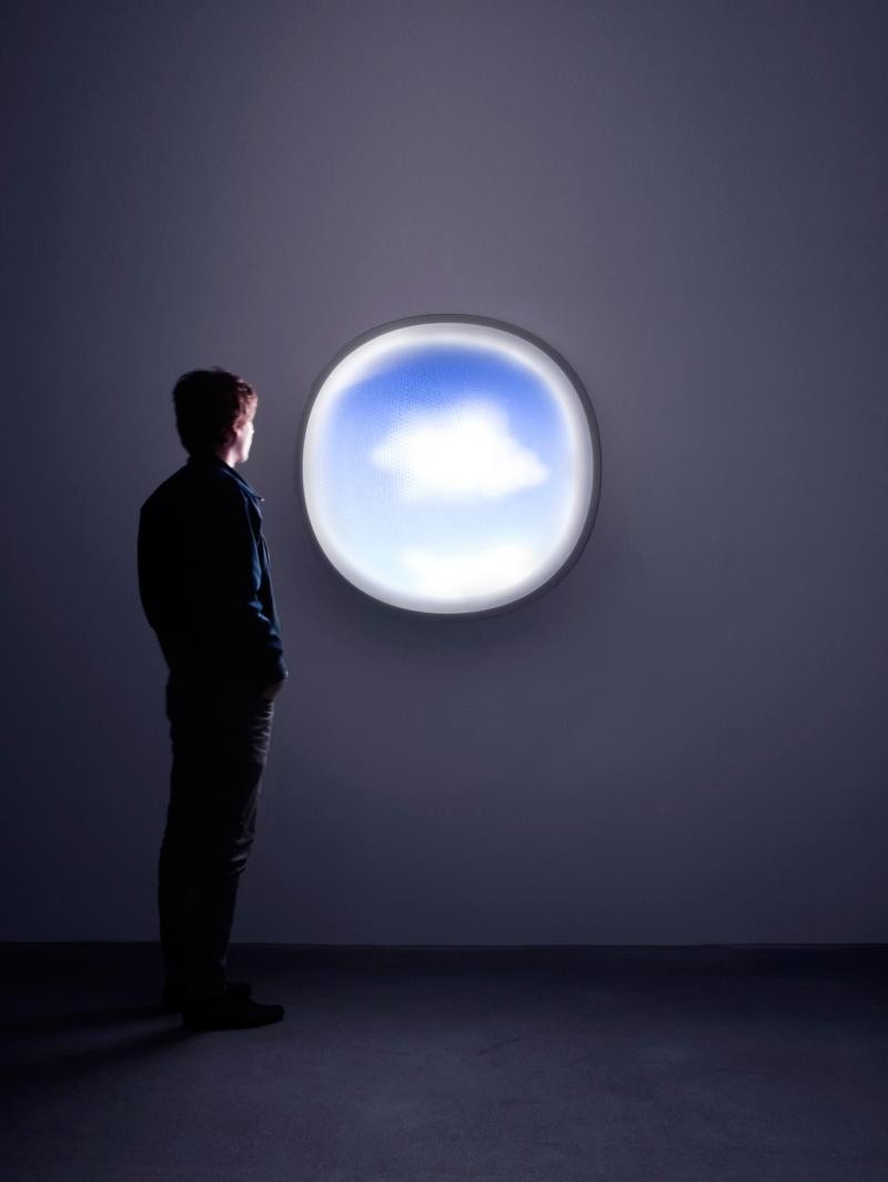 Man looking out a circular cloud-shaped window