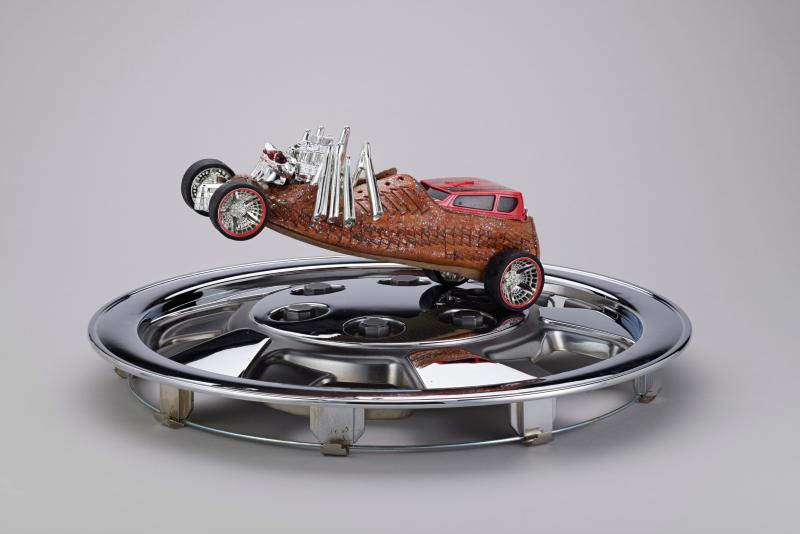 Mixed media sculpture of a car racing on a silver hubcap