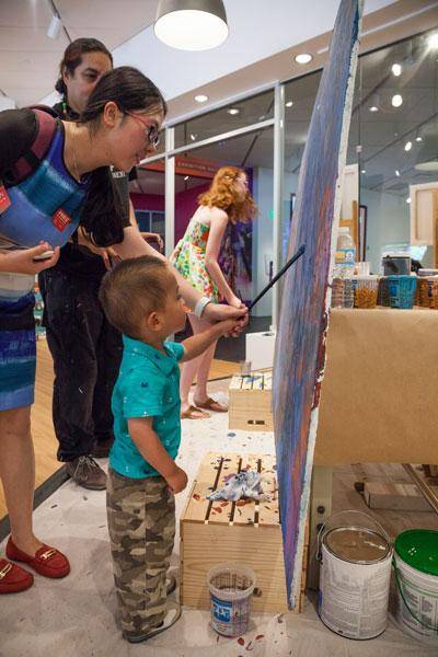 A mother helping a child paint at the Denver Art Museum on Free First Saturday.