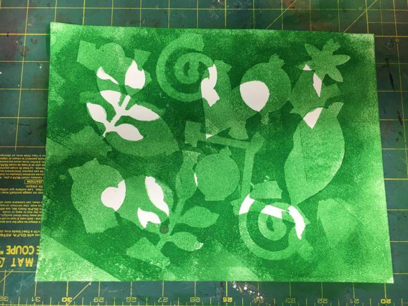 Overlapping green and white shapes are created on the paper.